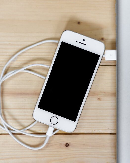 A smartphone charging on a wooden desk